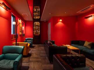 Luxurious red-walled lounge with plush leather seating and a built-in bar showcasing an impressive liquor collection.