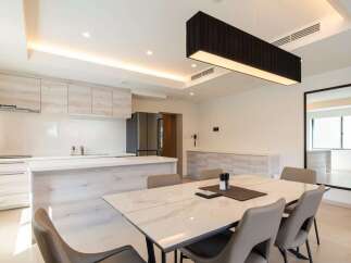 Modern kitchen with sleek cabinetry and island, open to a dining area with marble table and six chairs.