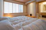 Experience serene living in this exquisitely designed bedroom, featuring a plush, white comforter and traditional Japanese shoji screens that filter soft, natural light.