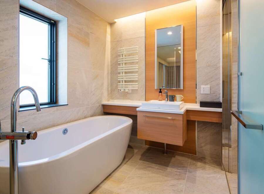 Luxurious bathroom boasts a freestanding bathtub, modern vanity with sleek cabinetry, and a frameless glass shower enclosure.