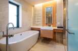 Luxurious bathroom boasts a freestanding bathtub, modern vanity with sleek cabinetry, and a frameless glass shower enclosure.