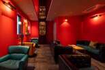 Luxurious red-walled lounge with plush leather seating and a built-in bar showcasing an impressive liquor collection.