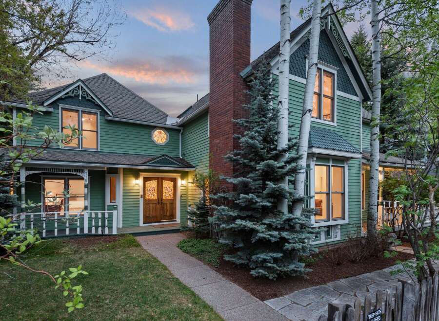 Charming Victorian home nestled in a serene landscape, featuring a spacious front porch and meticulously maintained gardens.