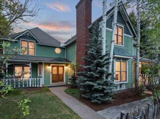 Charming Victorian home nestled in a serene landscape, featuring a spacious front porch and meticulously maintained gardens.