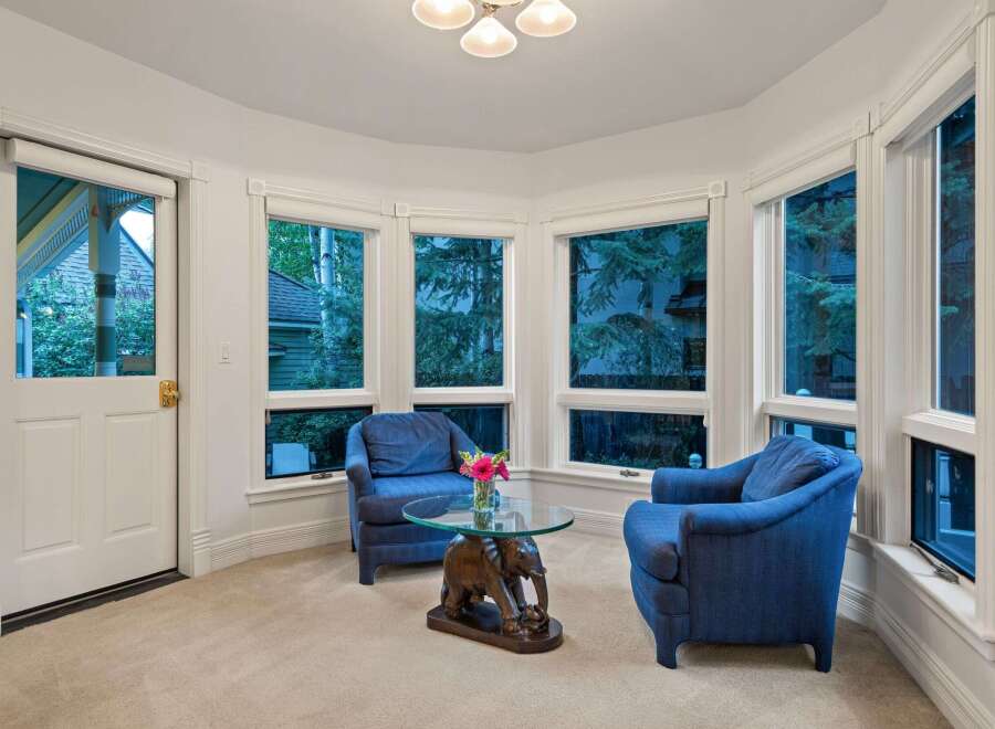 Sun-drenched sunroom boasts a cozy seating area with two armchairs and a unique elephant-shaped coffee table.