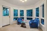 Sun-drenched sunroom boasts a cozy seating area with two armchairs and a unique elephant-shaped coffee table.