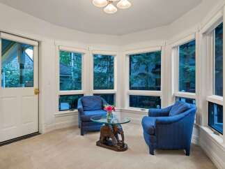 Sun-drenched sunroom boasts a cozy seating area with two armchairs and a unique elephant-shaped coffee table.