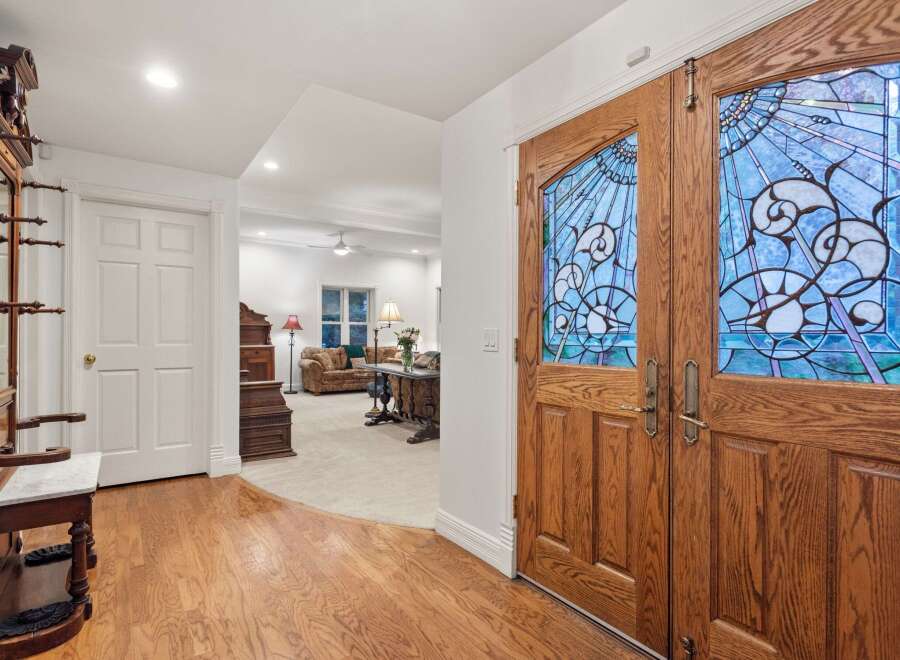 This stunning home features hardwood floors, an antique hall tree, and a beautiful stained-glass double door entryway.