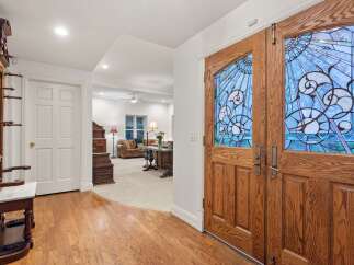 This stunning home features hardwood floors, an antique hall tree, and a beautiful stained-glass double door entryway.