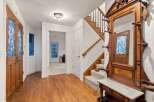 This stunning entryway boasts gleaming hardwood floors, an antique hall tree, and elegant stained-glass doors.