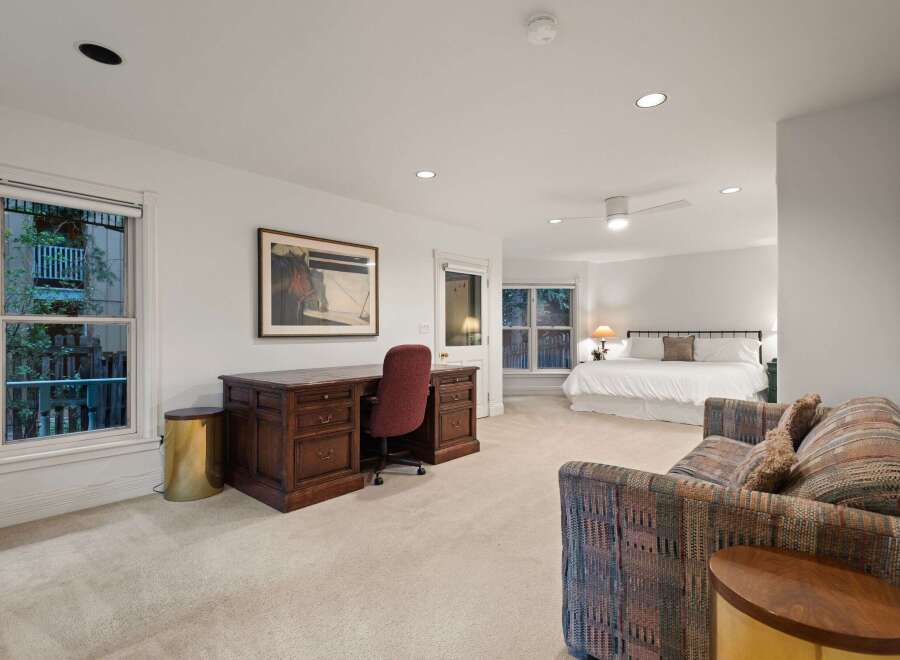 This spacious master suite boasts a king-size bed, a sitting area with a comfortable couch, and a large desk perfect for working from home.