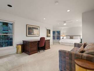 This spacious master suite boasts a king-size bed, a sitting area with a comfortable couch, and a large desk perfect for working from home.