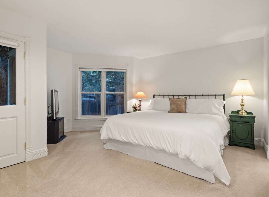 This luxurious bedroom boasts a plush king-size bed, dressed in crisp white linens, and complemented by a cozy carpet.