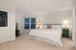 This luxurious bedroom boasts a plush king-size bed, dressed in crisp white linens, and complemented by a cozy carpet.