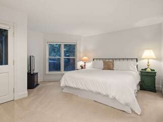 This luxurious bedroom boasts a plush king-size bed, dressed in crisp white linens, and complemented by a cozy carpet.