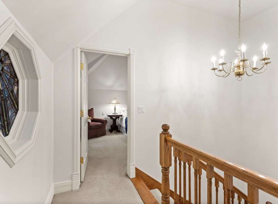 Elegant hallway with stained glass window and hardwood staircase leading to upper level.