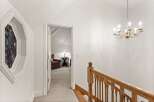 Elegant hallway with stained glass window and hardwood staircase leading to upper level.