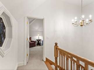 Elegant hallway with stained glass window and hardwood staircase leading to upper level.