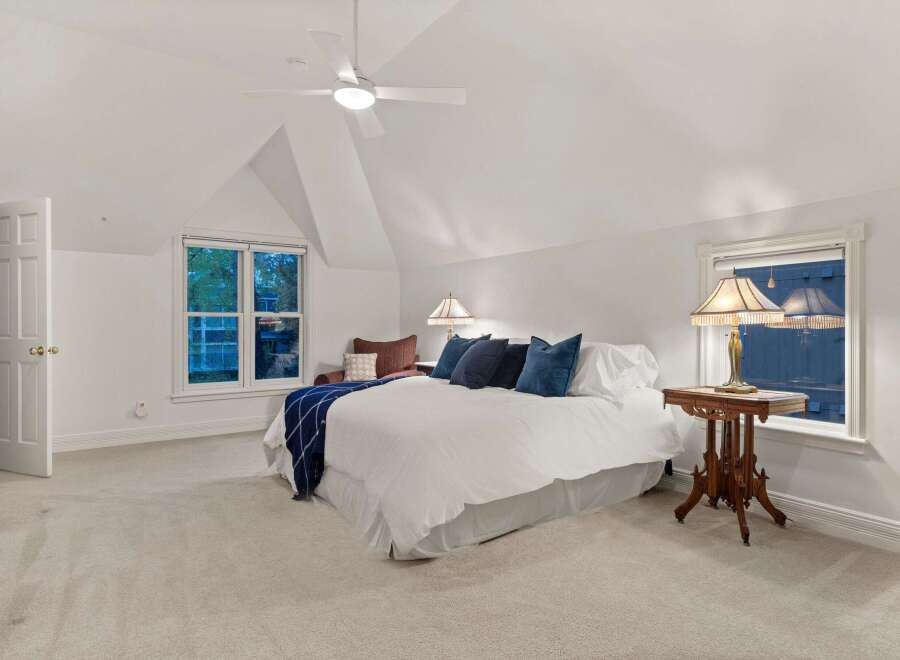 This bedroom boasts a serene atmosphere with its vaulted ceiling and plush carpeting.