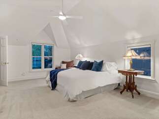 This bedroom boasts a serene atmosphere with its vaulted ceiling and plush carpeting.