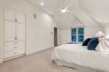 This bright and airy bedroom boasts a vaulted ceiling, complemented by a ceiling fan for optimal comfort.