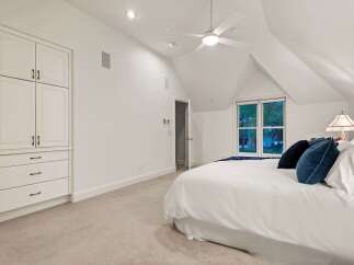 This bright and airy bedroom boasts a vaulted ceiling, complemented by a ceiling fan for optimal comfort.