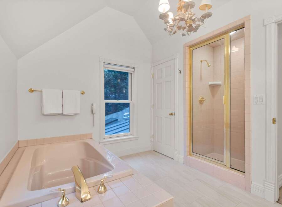 This charming bathroom boasts a vintage-inspired pink tile design, complemented by elegant gold fixtures.