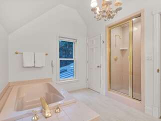 This charming bathroom boasts a vintage-inspired pink tile design, complemented by elegant gold fixtures.