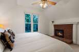 Cozy up by the fireplace in this charming bedroom, featuring a comfortable king-size bed and a large window offering scenic views.