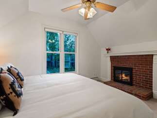 Cozy up by the fireplace in this charming bedroom, featuring a comfortable king-size bed and a large window offering scenic views.