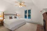 Relax in this cozy bedroom featuring a king-size bed, a ceiling fan, and a fireplace.