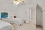Charming bedroom with twin beds, white wicker dresser, and a ceiling fan.