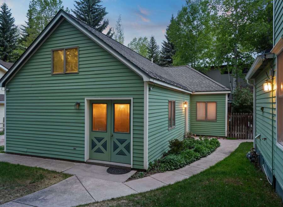 Charming green house with a spacious backyard and well-maintained landscaping.