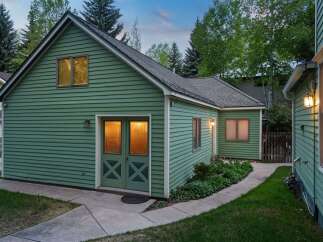 Charming green house with a spacious backyard and well-maintained landscaping.
