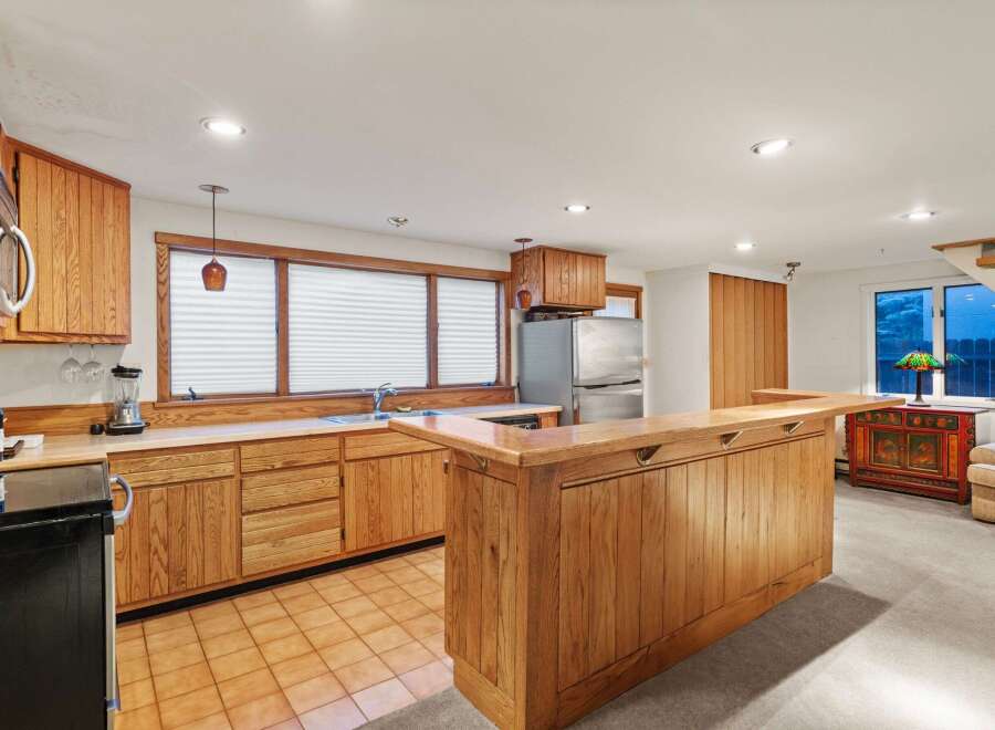 This stunning kitchen boasts beautiful wood cabinetry, a spacious island with seating, and a tile floor.
