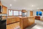 This stunning kitchen boasts beautiful wood cabinetry, a spacious island with seating, and a tile floor.
