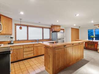 This stunning kitchen boasts beautiful wood cabinetry, a spacious island with seating, and a tile floor.