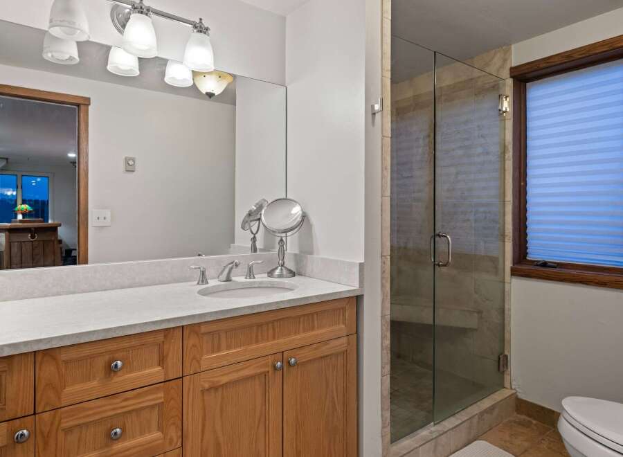 This stunning bathroom boasts a spacious vanity with ample storage, complemented by a sleek, frameless glass shower enclosure.