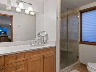 This stunning bathroom boasts a spacious vanity with ample storage, complemented by a sleek, frameless glass shower enclosure.