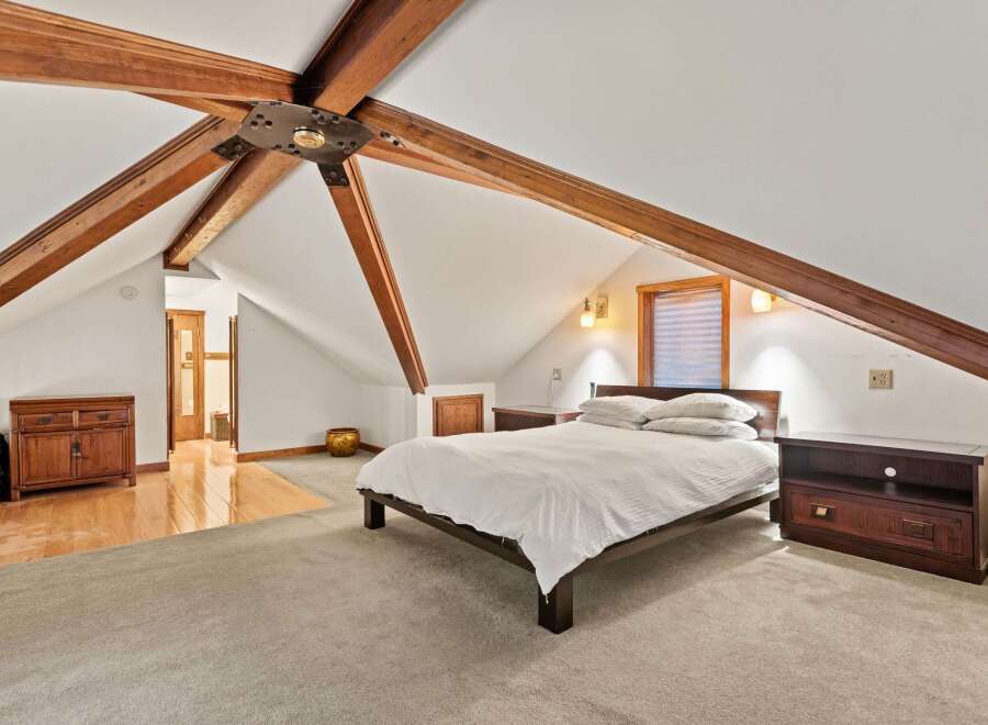 This attic bedroom boasts a charming and unique design with exposed wooden beams, creating a cozy and spacious atmosphere.