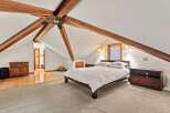 This attic bedroom boasts a charming and unique design with exposed wooden beams, creating a cozy and spacious atmosphere.
