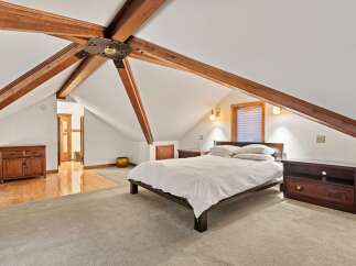 This attic bedroom boasts a charming and unique design with exposed wooden beams, creating a cozy and spacious atmosphere.