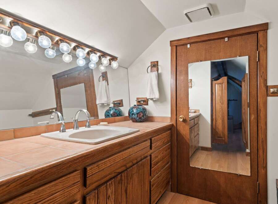 This charming bathroom boasts a vanity with a lovely wooden finish, complemented by a tiled countertop and a stylish sink.
