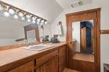 This charming bathroom boasts a vanity with a lovely wooden finish, complemented by a tiled countertop and a stylish sink.