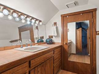 This charming bathroom boasts a vanity with a lovely wooden finish, complemented by a tiled countertop and a stylish sink.