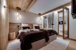 Cozy chalet bedroom with twin beds, wooden walls, and a plush brown throw.