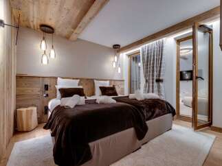 Cozy chalet bedroom with twin beds, wooden walls, and a plush brown throw.