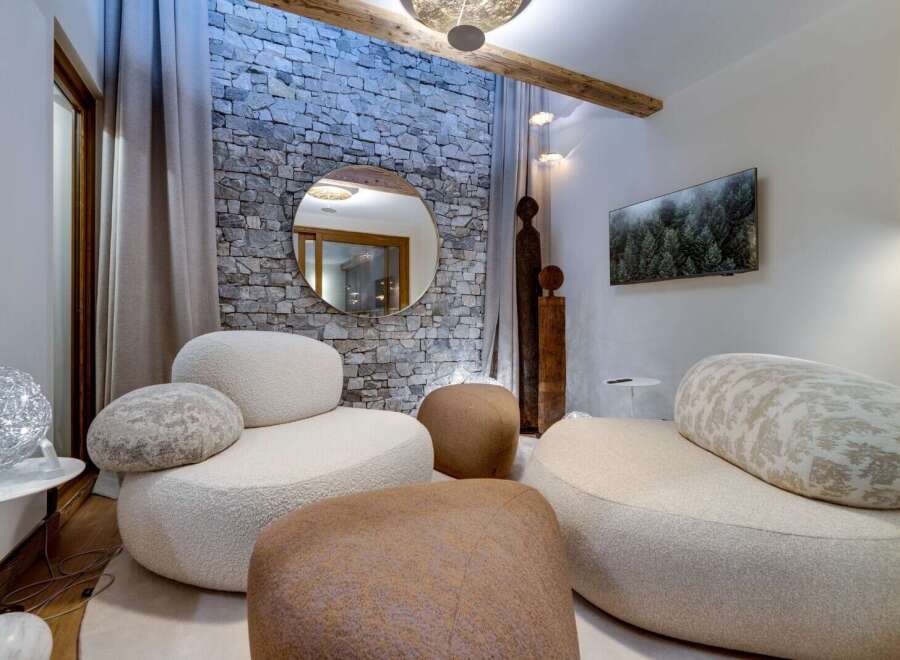 Relax in style in this luxurious living room, featuring a stunning stone wall, plush seating, and modern decor.