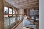 This stunning chalet boasts a breathtaking mountain view from its arched window, complemented by a rustic wooden ceiling and stone wall.