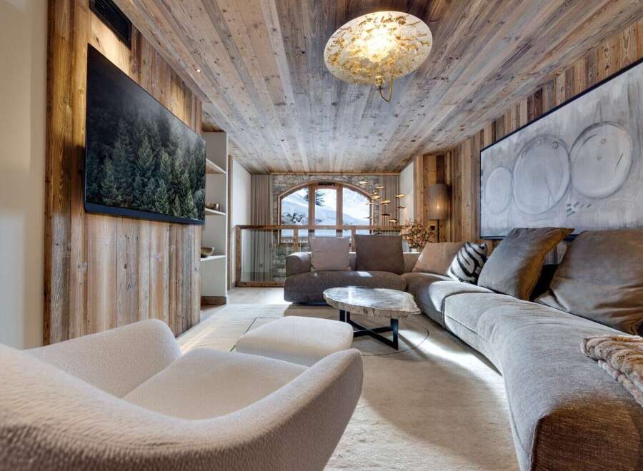 Luxury chalet living room with stunning mountain views, featuring a large sectional sofa, a statement coffee table, and a cozy fireplace.